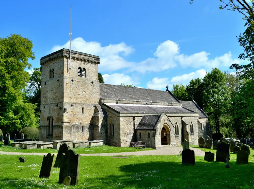 Photo de Église de St Michael et couverture grave se penchant sur le contrefort à côté de la porte nord - Historic England